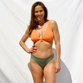 Woman wearing orange bikini top and khaki bottom by Paupa, front view