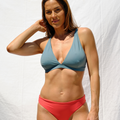 Woman wearing a stone blue bikini top and red bottom by Paupa, front view
